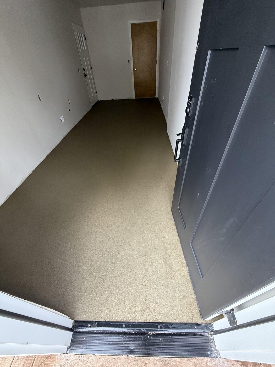 A finished mortar bed running flat down a hallway to an exterior door threshold.